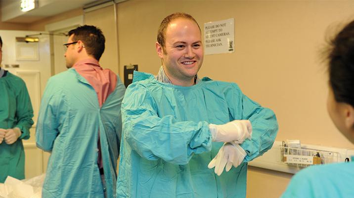 A group of surgeons putting on surgical gowns and gloves