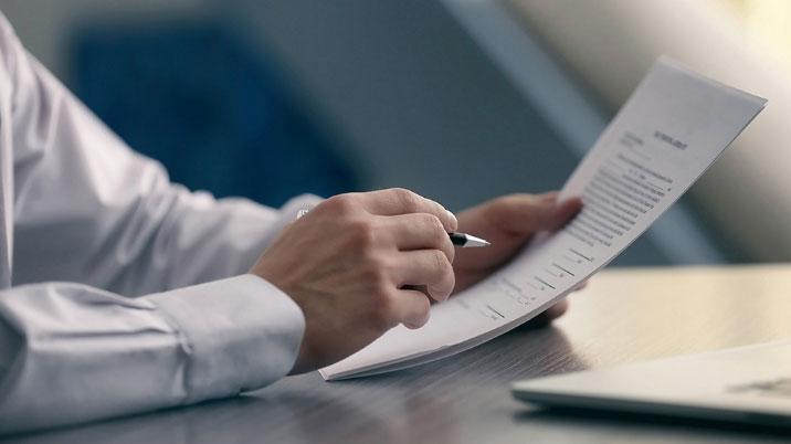 Person with a pen looking over a CV